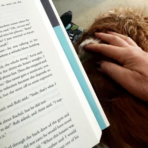 Angelina Eynon reading a novel while her dog Alfie rests beside her